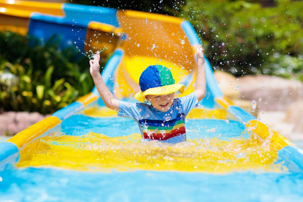 Kids on water slide in aqua park. Summer vacation